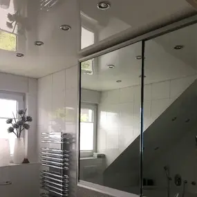 Modernes Badezimmer mit Spiegelschrank, weißen Fliesen und verchromtem Handtuchheizkörper.