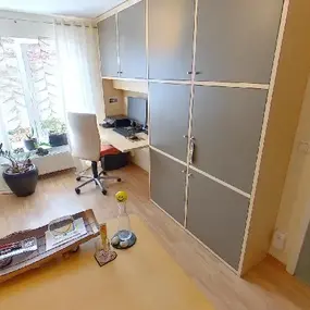 Modernes, helles Homeoffice mit großem Einbauschrank, Schreibtisch und ergonomischem Stuhl.