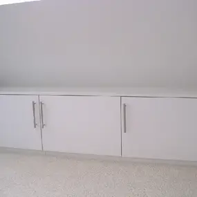 Weißer Einbauschrank mit drei Türen und Metallgriffen unter einer Dachschräge im Raum.